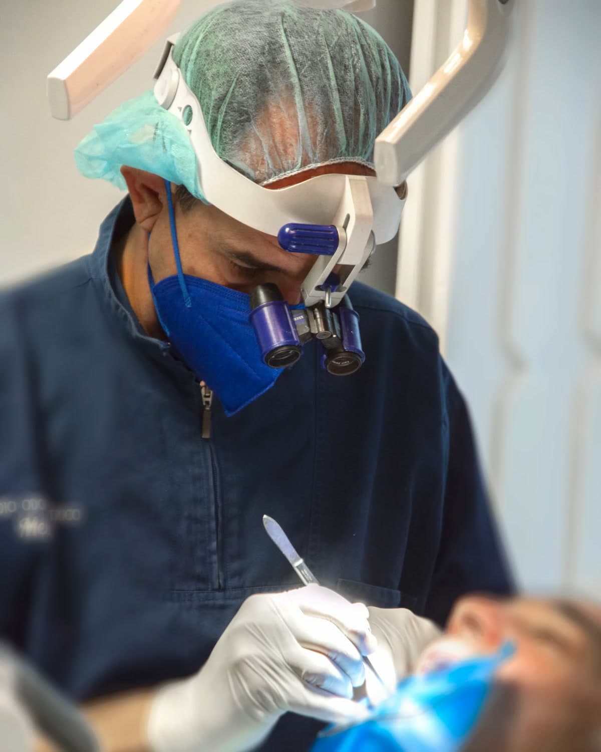 Il dott. Dario Melilli al lavoro con cuffia, mascherina e occhiali ingrandenti con luce frontale
